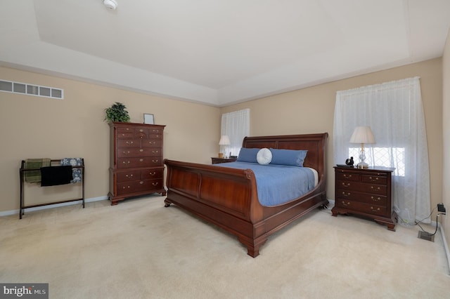 bedroom with carpet floors, a tray ceiling, and visible vents