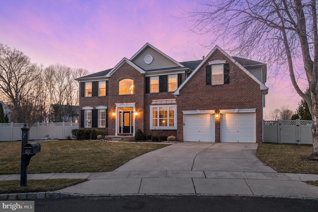 view of front facade featuring a yard, brick siding, fence, and driveway