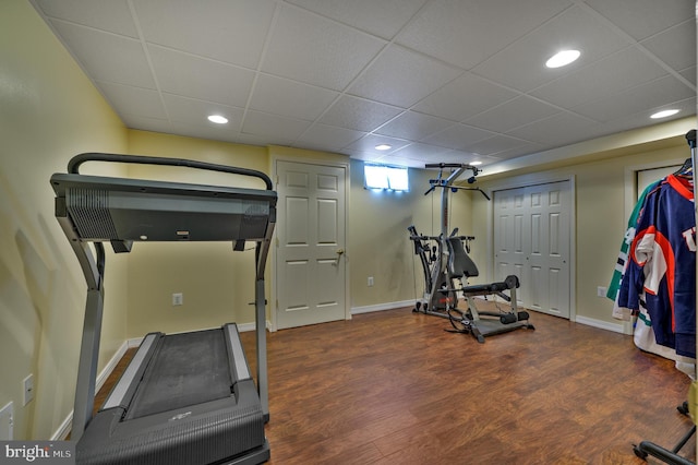 exercise room with a drop ceiling, recessed lighting, wood finished floors, and baseboards