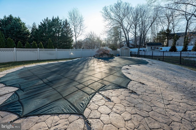 view of pool featuring a storage shed, a fenced backyard, and a patio