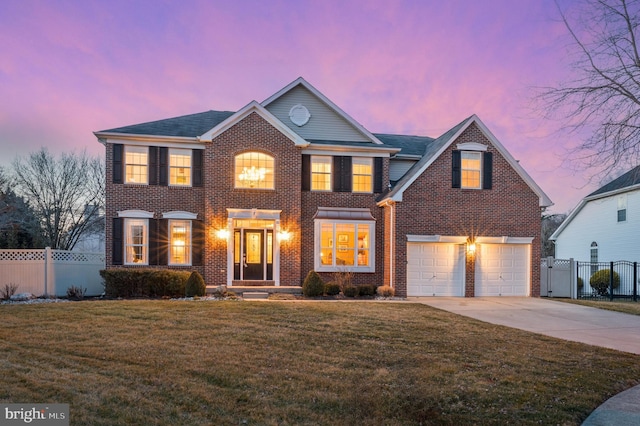 view of front of house featuring a lawn, fence, concrete driveway, and brick siding