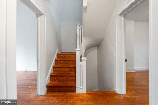 staircase with baseboards and wood finished floors