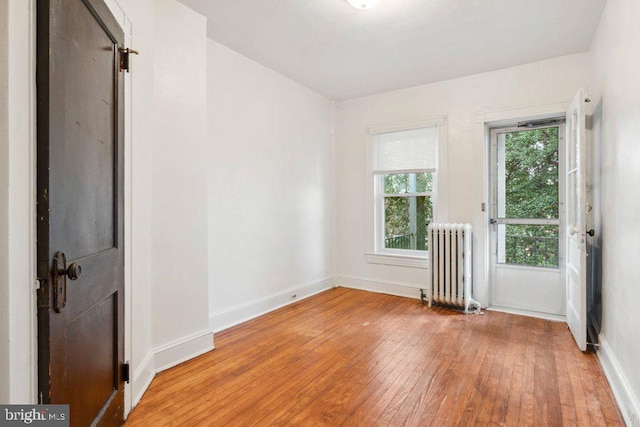 empty room with baseboards, hardwood / wood-style flooring, and radiator