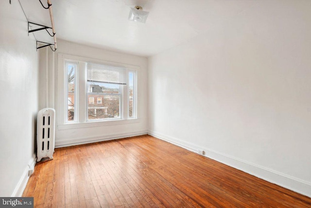 unfurnished room with light wood-type flooring, radiator heating unit, and baseboards