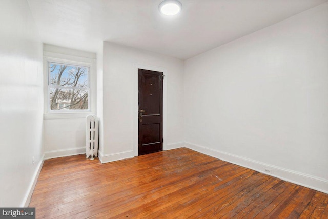 unfurnished room featuring radiator heating unit, baseboards, and hardwood / wood-style floors