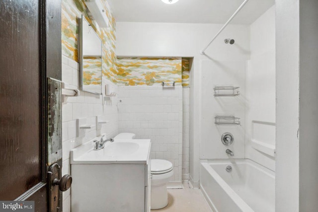 bathroom featuring tile walls, toilet, vanity, and shower / tub combination