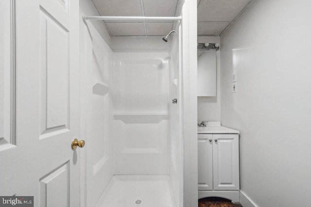 bathroom featuring walk in shower, vanity, and baseboards