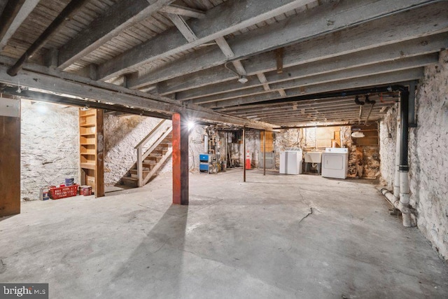 unfinished below grade area featuring washing machine and dryer, stairway, and a sink