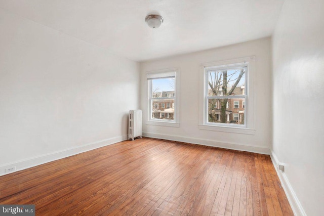 empty room with light wood-type flooring, radiator, and baseboards