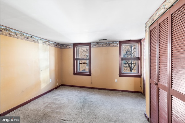 unfurnished bedroom with a closet, carpet flooring, visible vents, and baseboards