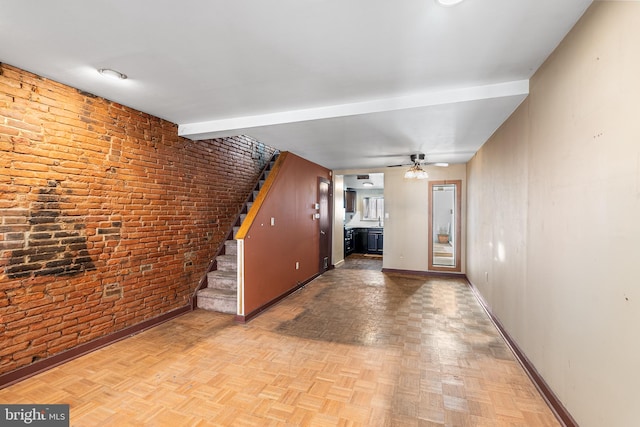 interior space with stairs, brick wall, a ceiling fan, and baseboards