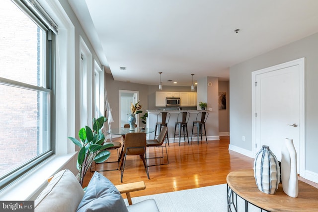 living area featuring light wood-type flooring, a wealth of natural light, visible vents, and baseboards