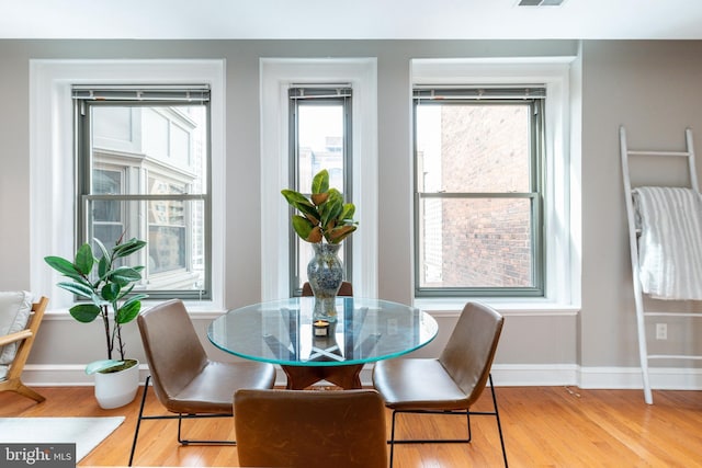 dining room with light wood-style floors, visible vents, and baseboards