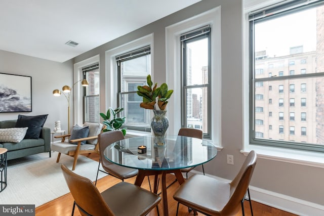 dining room featuring baseboards, visible vents, and wood finished floors