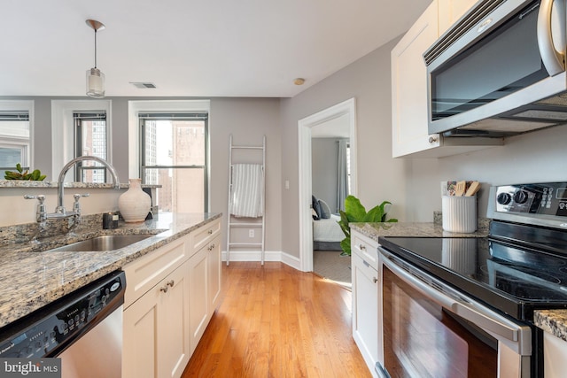 kitchen featuring stainless steel appliances, a sink, visible vents, white cabinetry, and light wood finished floors