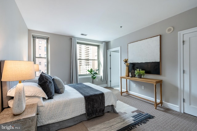 carpeted bedroom with visible vents, multiple windows, and baseboards