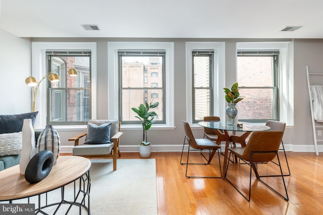 dining space with light wood-style flooring, visible vents, and baseboards