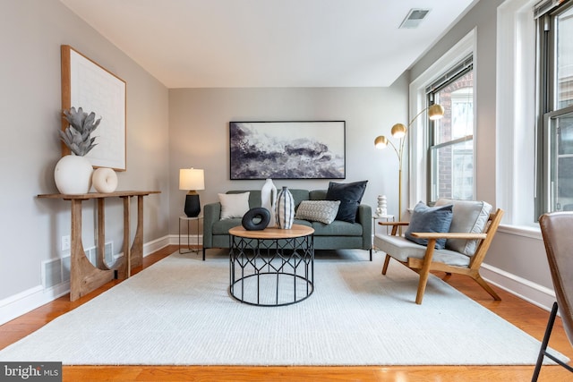 sitting room with baseboards, visible vents, and wood finished floors