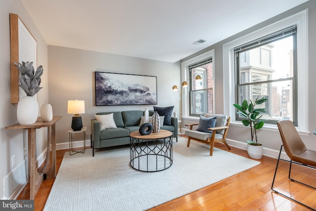 living room featuring light wood-type flooring, visible vents, and baseboards