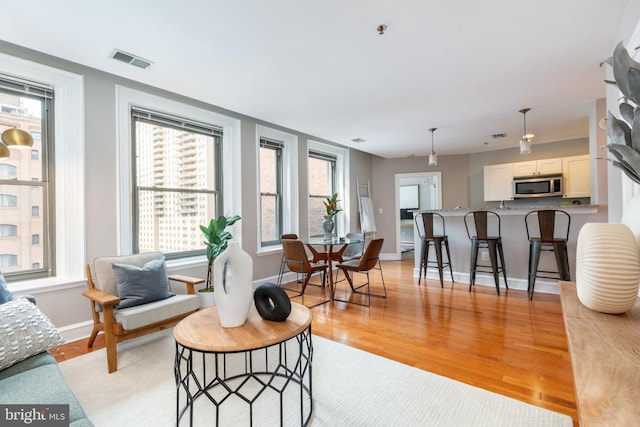 living room featuring baseboards, visible vents, and light wood finished floors