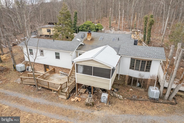 exterior space featuring roof with shingles, a chimney, central AC unit, a sunroom, and a deck