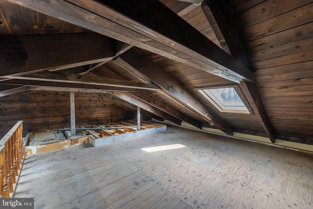 unfinished attic with a skylight and an upstairs landing