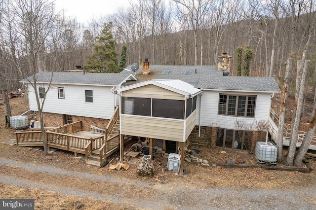 back of property with stairs, a chimney, and a sunroom