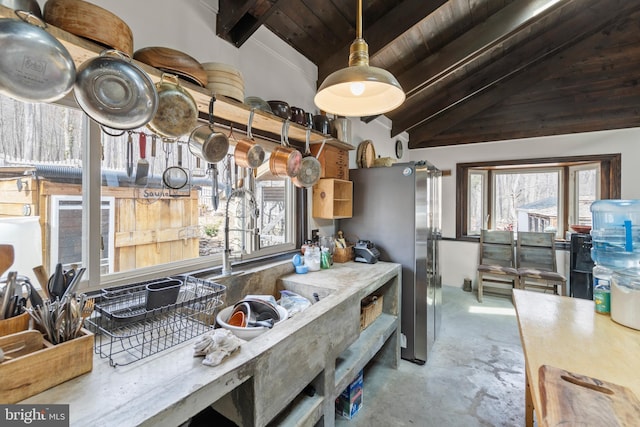 kitchen featuring lofted ceiling with beams, concrete floors, wooden ceiling, and freestanding refrigerator