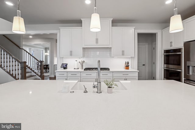 kitchen with stainless steel double oven, white cabinets, light countertops, fridge with ice dispenser, and tasteful backsplash