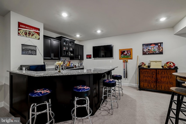 bar featuring light colored carpet, baseboards, indoor bar, and recessed lighting