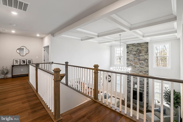 corridor featuring a healthy amount of sunlight, beam ceiling, visible vents, and wood finished floors