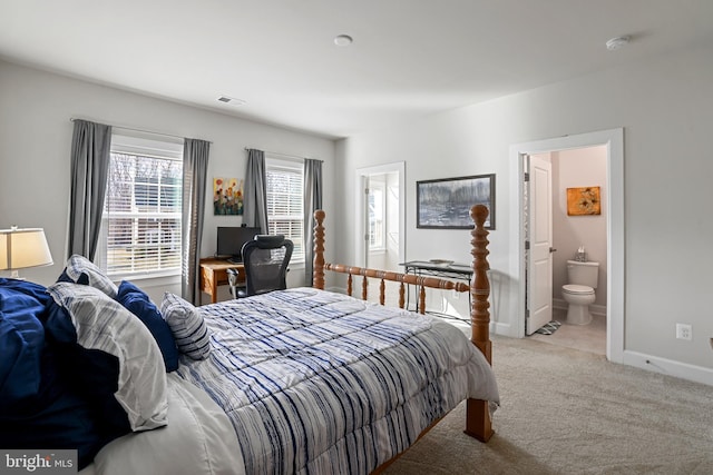 carpeted bedroom featuring ensuite bath, visible vents, and baseboards