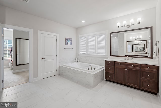 full bathroom featuring marble finish floor, recessed lighting, a garden tub, and vanity