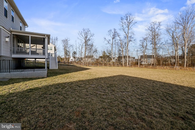 view of yard with a sunroom, stairs, and fence