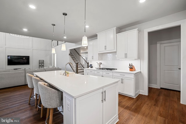 kitchen featuring dark wood finished floors, decorative backsplash, open floor plan, white cabinetry, and a sink