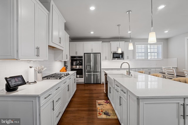 kitchen featuring appliances with stainless steel finishes, a sink, dark wood finished floors, and white cabinets