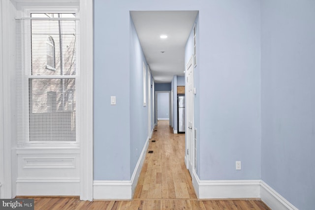 corridor featuring baseboards and light wood-style floors