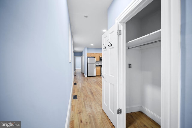 hallway featuring light wood-type flooring, baseboards, and recessed lighting