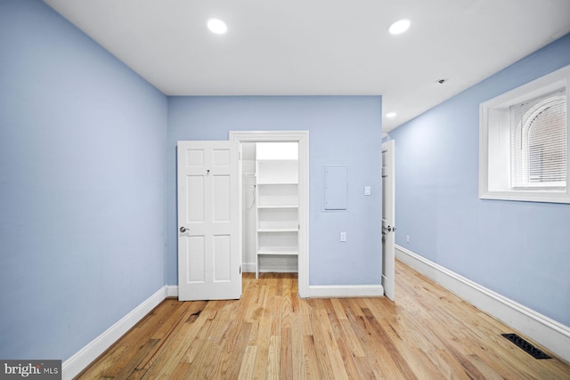 unfurnished bedroom featuring a walk in closet, light wood finished floors, recessed lighting, visible vents, and baseboards