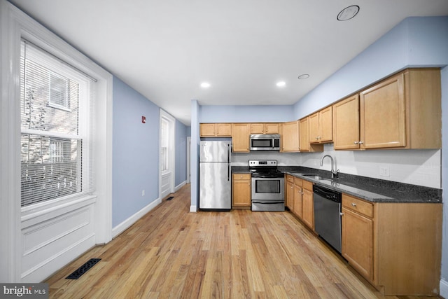 kitchen featuring appliances with stainless steel finishes, plenty of natural light, light wood-style floors, and a sink