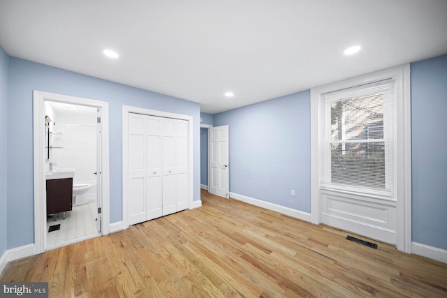 unfurnished bedroom featuring baseboards, visible vents, wood finished floors, ensuite bathroom, and recessed lighting