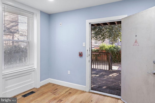 doorway with light wood-type flooring, visible vents, and baseboards