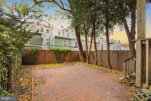 patio terrace at dusk featuring a fenced backyard