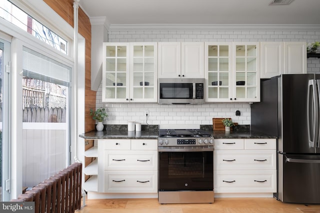 kitchen with stainless steel appliances, white cabinetry, ornamental molding, backsplash, and glass insert cabinets