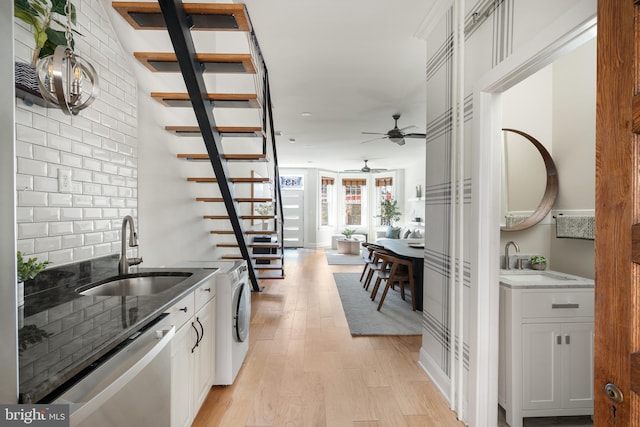 kitchen featuring a sink, light wood-type flooring, light stone counters, and dishwasher