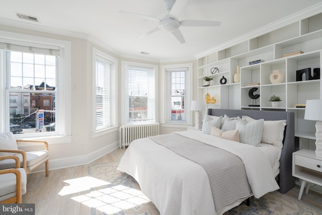 bedroom featuring radiator, multiple windows, ornamental molding, and wood finished floors