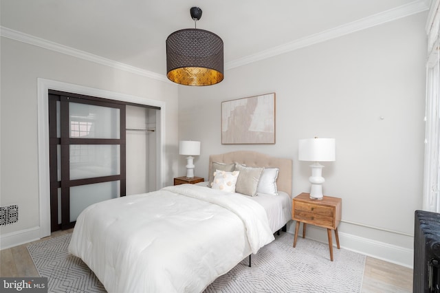 bedroom featuring light wood finished floors, ornamental molding, and baseboards