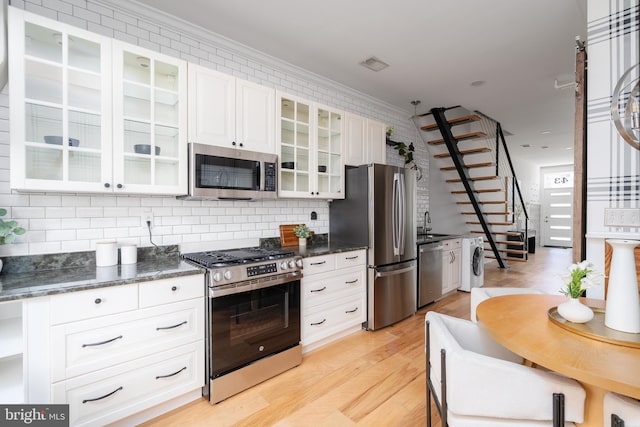 kitchen with stainless steel appliances, visible vents, light wood-style floors, glass insert cabinets, and washer / dryer