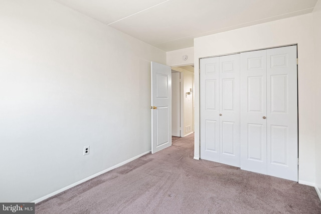 unfurnished bedroom featuring a closet, baseboards, and carpet flooring