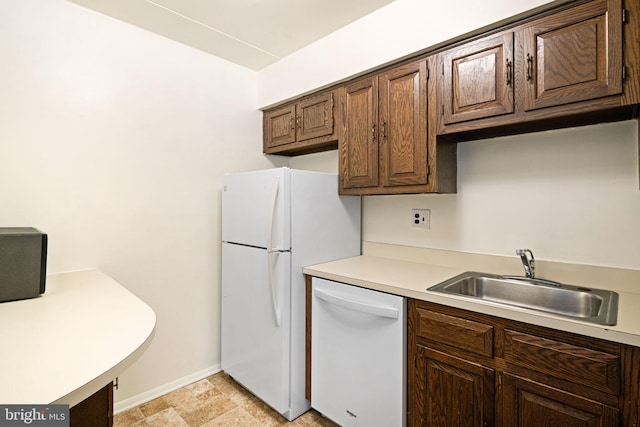 kitchen with white appliances, light countertops, dark brown cabinetry, and a sink